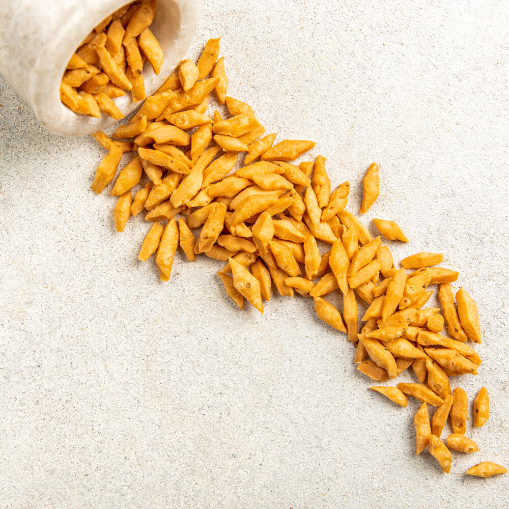 Mini diamond shaped crispy barik nimki pieces coming out of a bowl. This namkeen is perfect for tea time snacks.