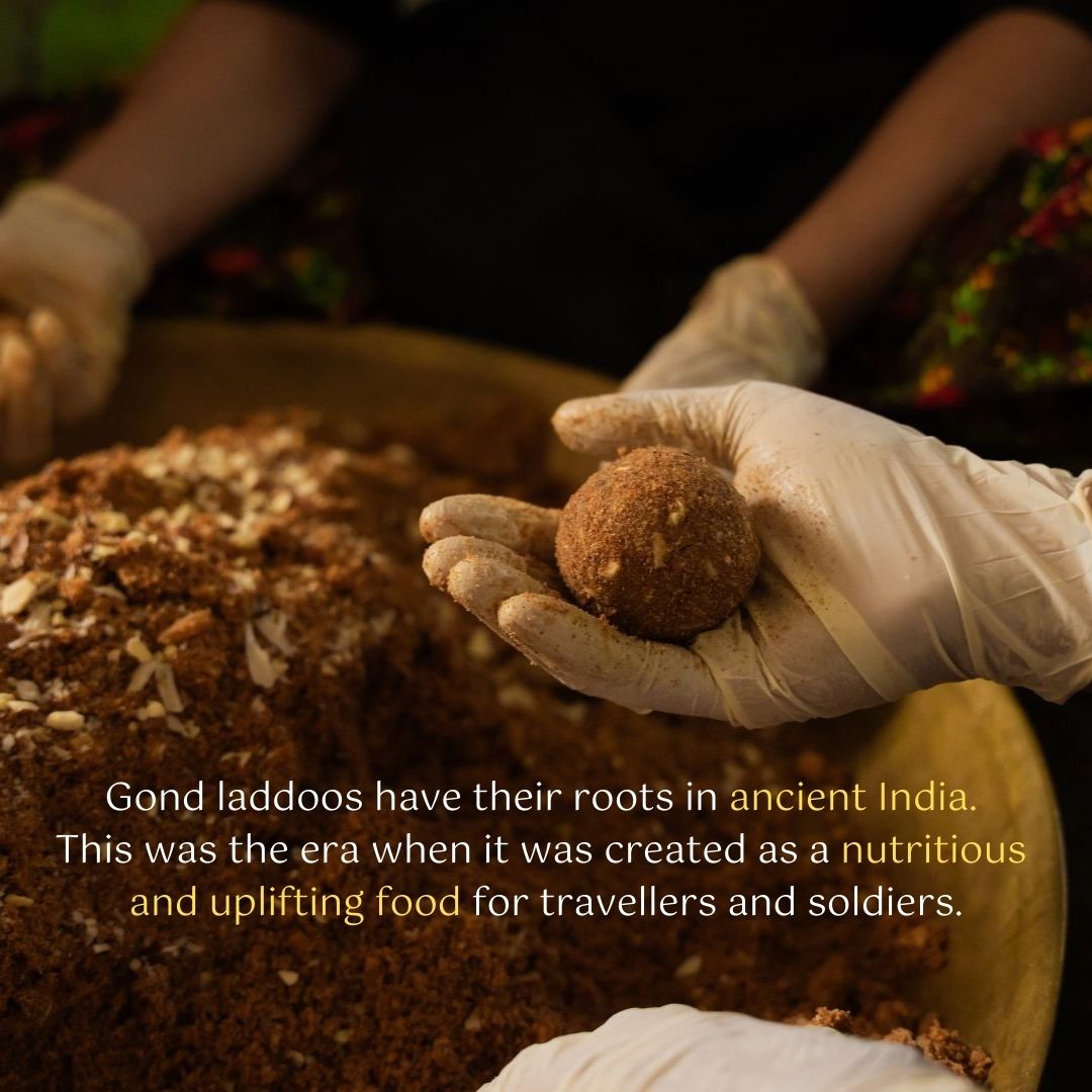 Image of people's hands making gond gud laddu with the text "Gond laddus have their roots in ancient India. This was the era when it was created as a nutritious and uplifting food for travellers and soldiers"
