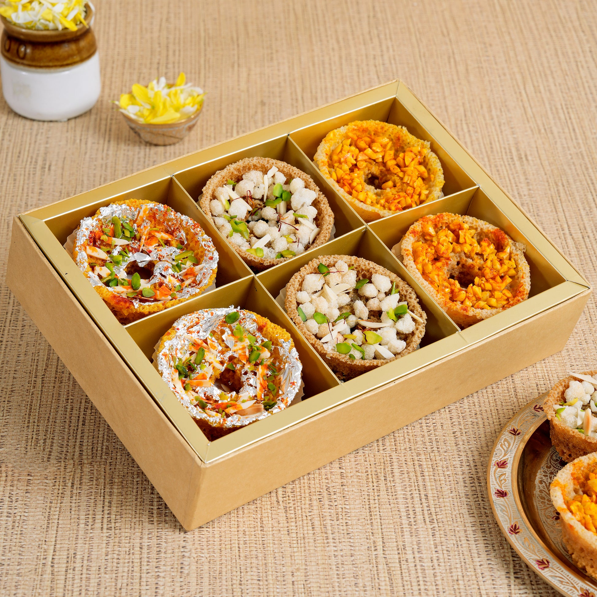 Box of assorted mini ghewars on a textured surface