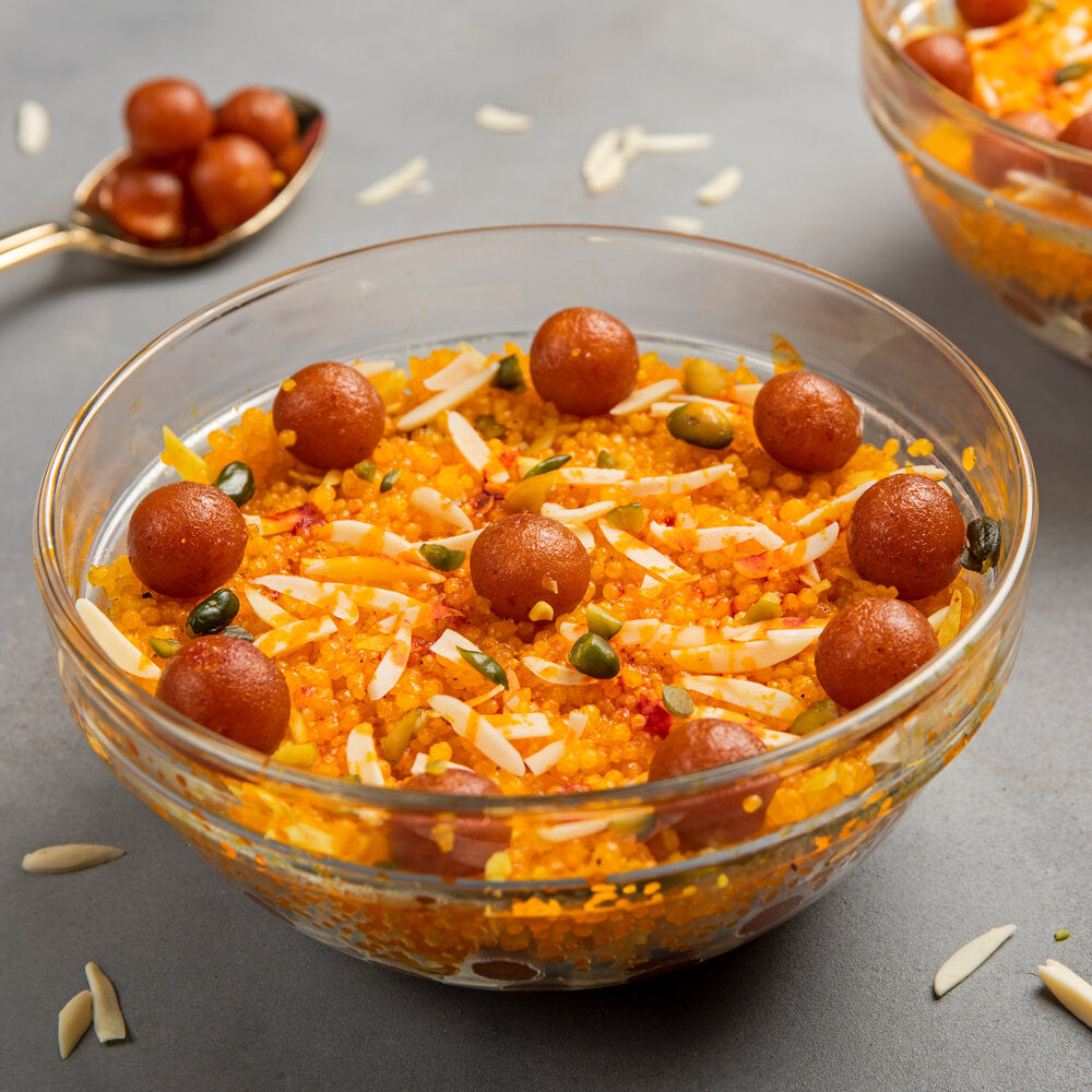 Bowl of boondi with pieces of mini gulab jamun and slivers of dry fruit.