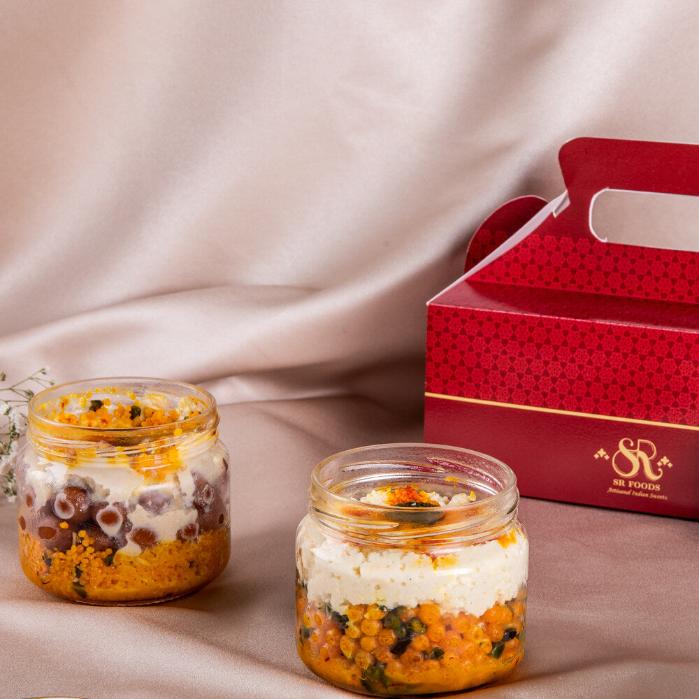 Two mithai jars placed side by side next to a decorative red box, showcasing an elegant packaging for gifting