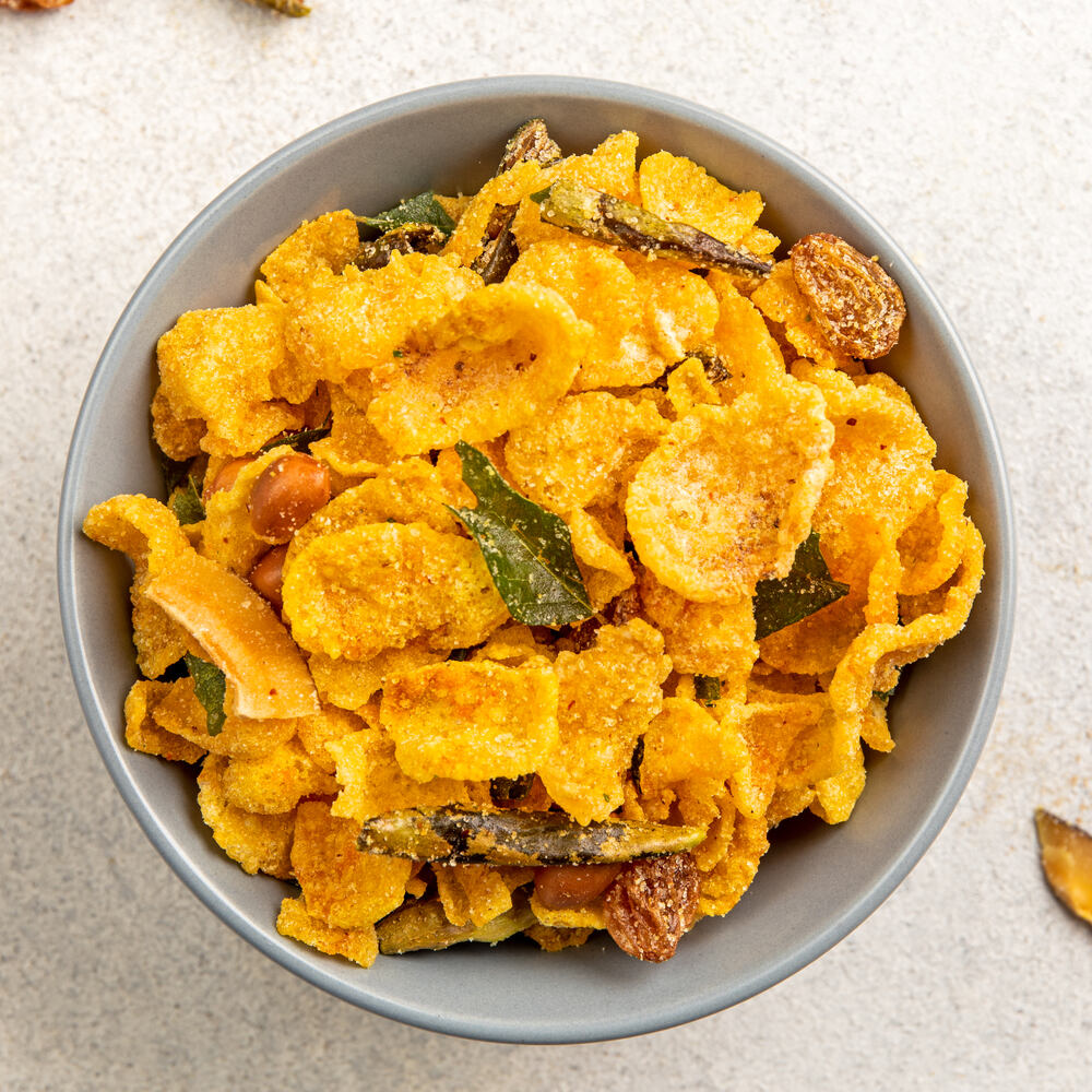 A bowl of crunchy corn flakes, mixed with an assortment of dry fruits and spices for a sweet, spicy, and nutty flavor.