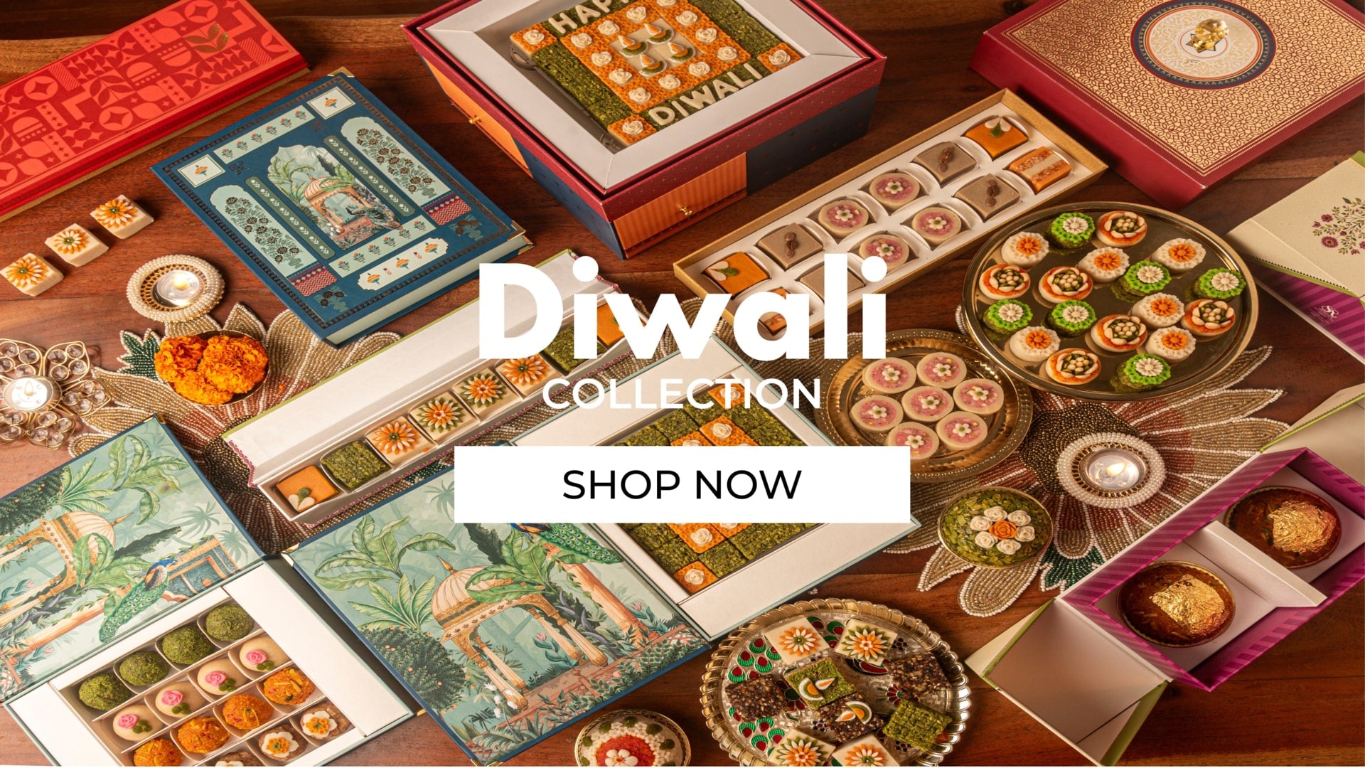 Diwali collection with colorful boxes and sweets on a wooden surface, featuring the text 'Diwali Collection' and 'Shop Now'.