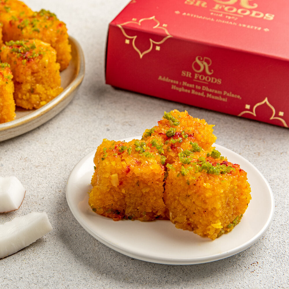 3 pieces of fresh nariyal barfi sitting on a plate, perfect for indulgence.