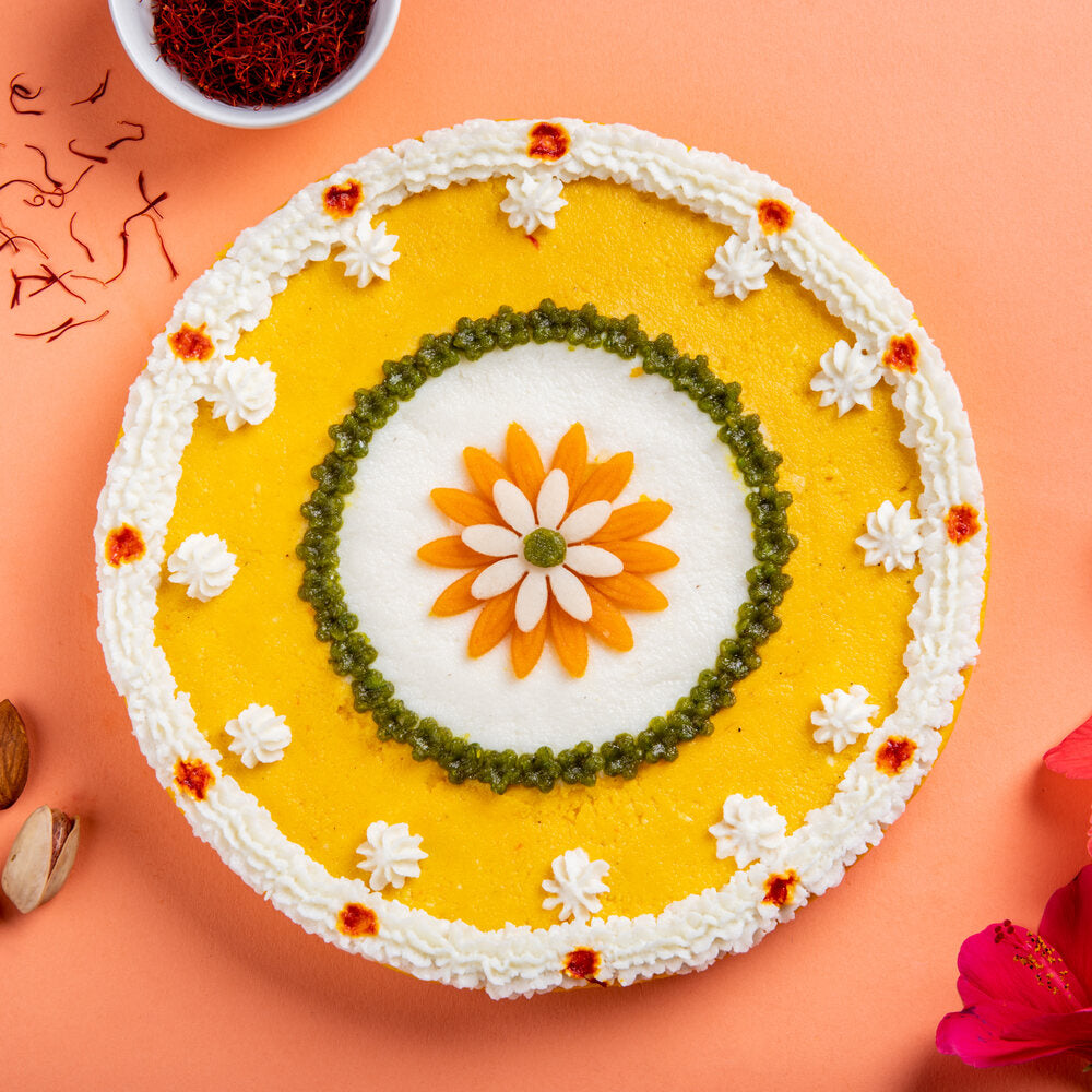 Circular mithai cake made of kesar and rose sandesh with a beautiful floral decoration on top, perfect for any festive occasion