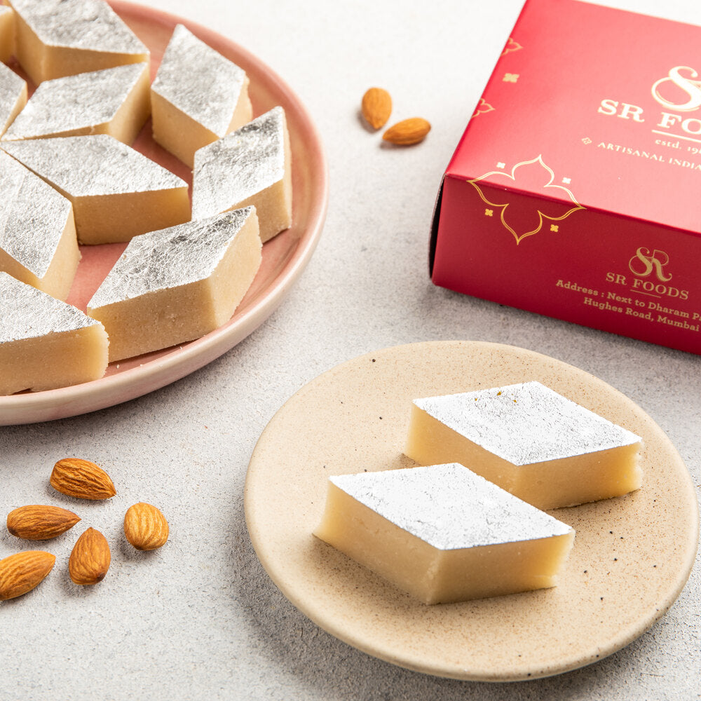 Beautifully crafted mamra badam barfi pieces cut into diamond shape pieces and adorned with silver varak