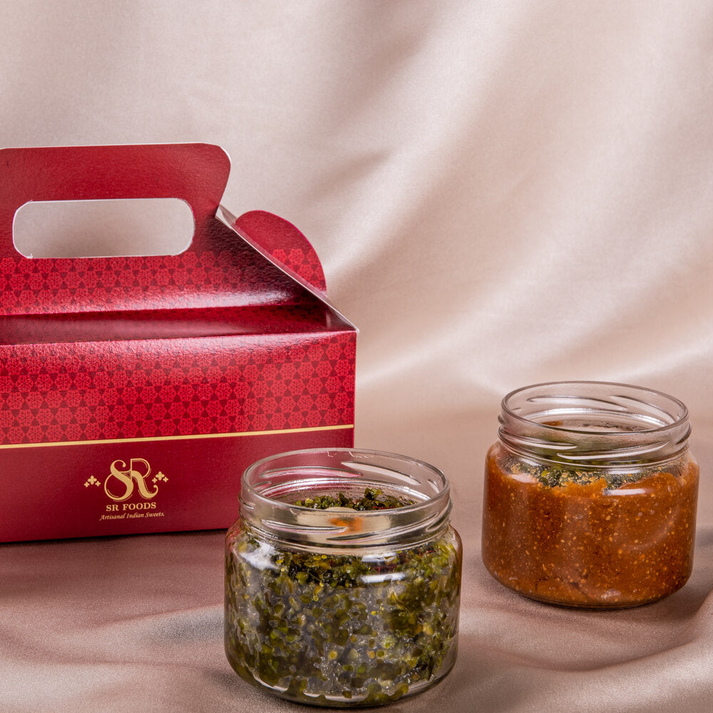 Two mithai jars placed side by side next to a decorative red box, showcasing an elegant packaging for gifting