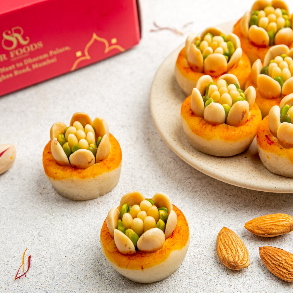 Mamra badam barfi in a disc shape adorned with pinenuts and mixed dry-druits in a flower shape