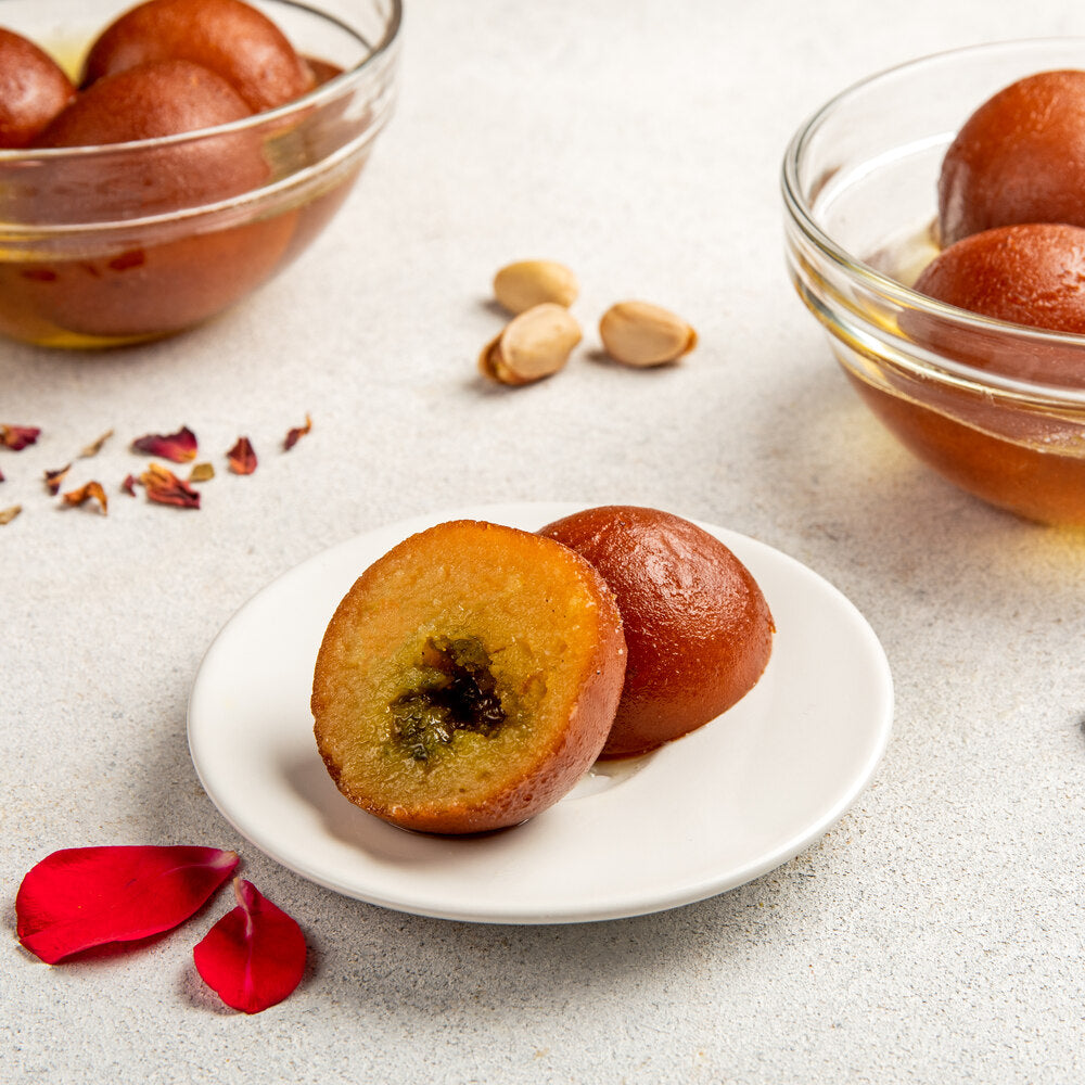 Gulab jamun piece broken into two with pistachio filling in the core.