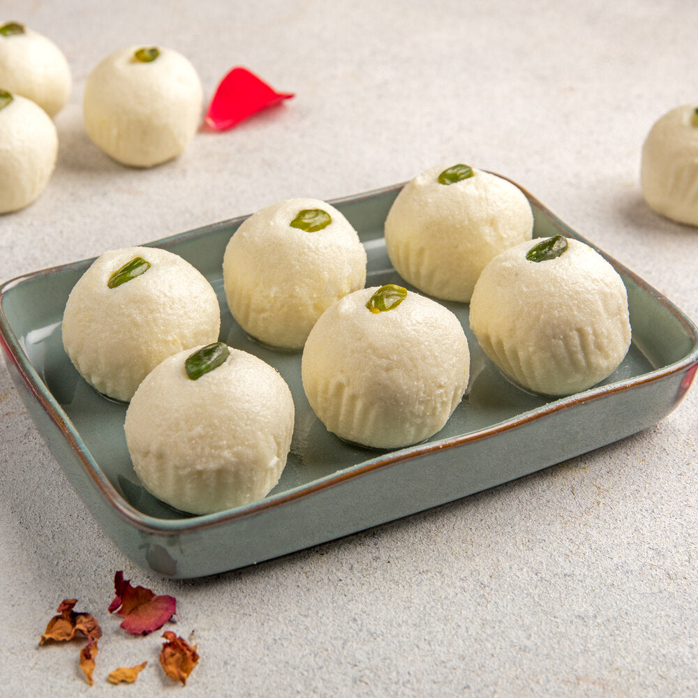 Beautifully crafted pieces of rose sandesh in a tray each adorned with a piece of pistachio